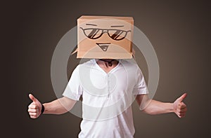 Young man gesturing with a cardboard box on his head with smiley