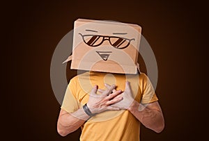 Young man gesturing with a cardboard box on his head with smiley