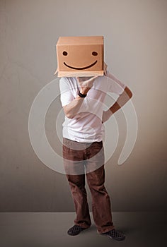 Young man gesturing with a cardboard box on his head with smiley