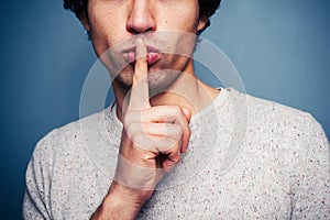 Young man gesturing hush with finger on lips