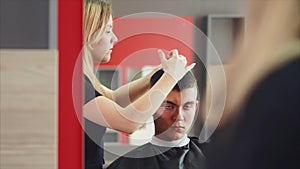 Young man getting haircut by female hairdresser while sitting in chair