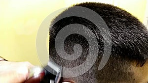 young man getting a haircut with a machine in a barbershop.