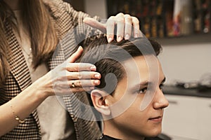 Young man getting a modern haircut. Hair salon master does hair styling client at barber shop. Men& x27;s fashion and