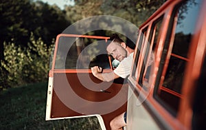 A young man getting out of a car on a roadtrip through countryside. Copy space.