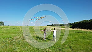 A young man and a girl running across the field. Couple launch flying kite. Family holiday.