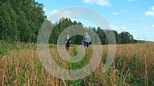 A young man and a girl with sports figures in sportswear are running along a cereal field.