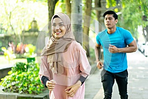a young man and a girl in a veil doing jogging together when outdoor exercise