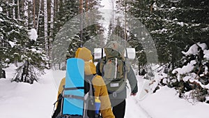 A young man and a girl are walking along a winter forest path.