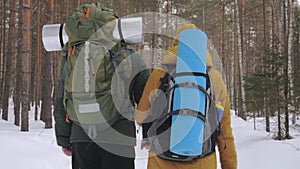 A young man and a girl are walking along a winter forest path.