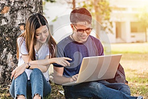 Young man and girls friend classmates sitting under tree consult