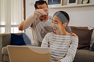 Young man giving his girlfriend a necklace as present. Asian woman getting surprised by her boyfriend with marriage