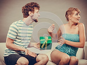 Young man giving offended woman gift box