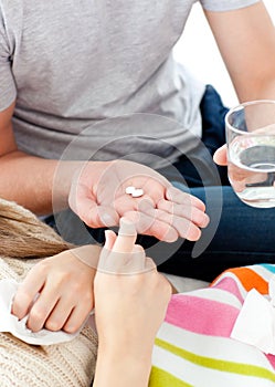 Young man giving pills to his morbid girlfriend