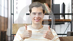 Young man giving thumb up as sign of success