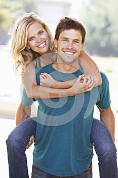 Young Man Giving Woman Piggyback Outdoors