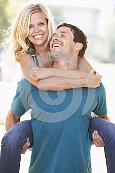 Young Man Giving Woman Piggyback Outdoors