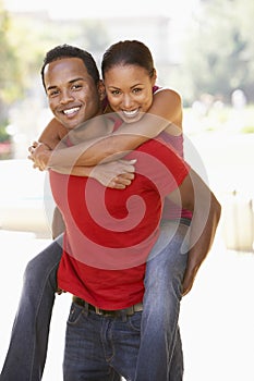 Young Man Giving Woman Piggyback Outdoors