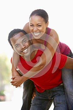 Young Man Giving Woman Piggyback Outdoors