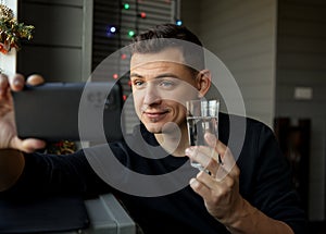 Young man with glass making facetime video calling to congratulate Merry Christmas his relatives.