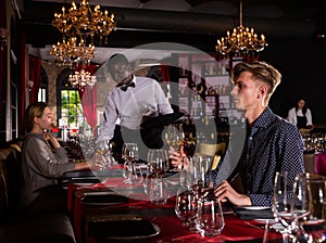 Young man with glass of white wine in fashionable restaurante.