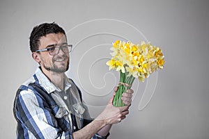 A young man with glasses and a bouquet of flowers