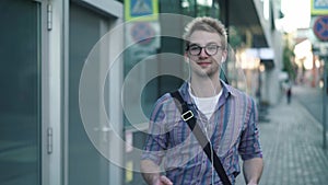 Young man in glasses enjoying his music while walking in the street
