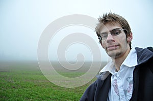 Young man with glasses in field