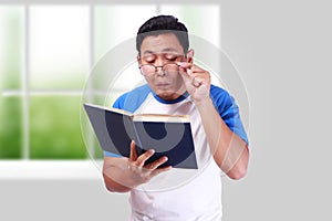 Young Man With Glasses Having Bad Vision When reading Book