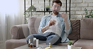 Young man in glasses having first grippe symptoms at home.