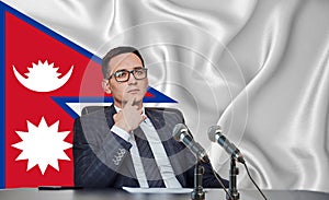 Young man in glasses and a jacket at an international meeting or press conference negotiations, on the background of the flag