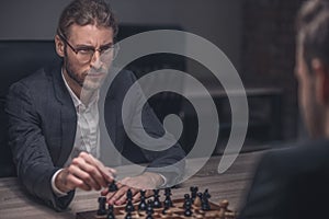 Young man with glasses making chess move