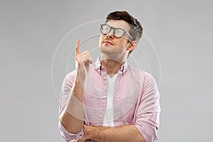 Young man in glasses pointing finger up