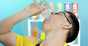 A young man with glasses pours a glass of ice over himself