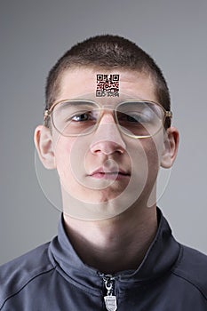 Young man with glasses presents a tattoo with a QR code on his forehead
