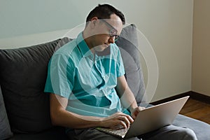 Young man in glasses speaking on the phone and looking on laptop screen