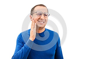 Young man in glasses suffering from toothache touching cheek on white background