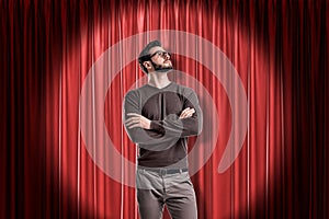 Young man with glasses wearing casual clothes on red stage curtains background