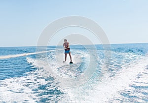 Young man glides on water skiing on the waves on the sea, ocean. Healthy lifestyle. Positive human emotions, feelings,