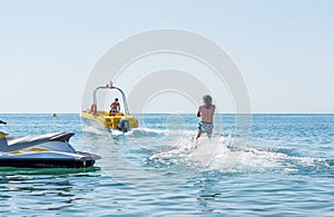 Young man glides on water skiing on the waves on the sea, ocean. Healthy lifestyle. Positive human emotions, feelings