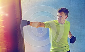 Young man in gloves boxing with punching bag