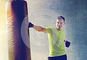 Young man in gloves boxing with punching bag