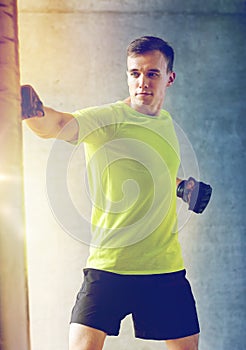 Young man in gloves boxing with punching bag