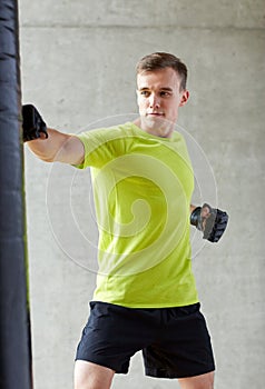 Young man in gloves boxing with punching bag