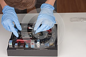 Young man with gloves installing part of CPU cooler fan.