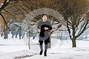 Young man goes jogging in winter while doing sports.