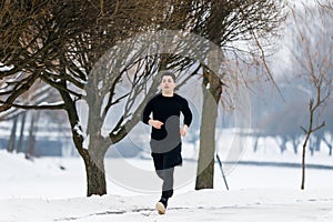 A young man goes jogging in winter while doing sports.