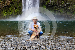 Young man and golden retriever reach the waterfall