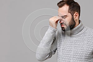 Young man in gray sweater posing isolated on grey background in studio. Healthy lifestyle, ill sick disease treatment