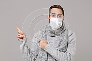 Young man in gray sweater, scarf isolated on grey background. Healthy lifestyle, ill disease treatment, cold season