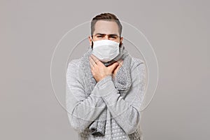 Young man in gray sweater, scarf isolated on grey background. Healthy lifestyle, ill sick disease treatment, cold season